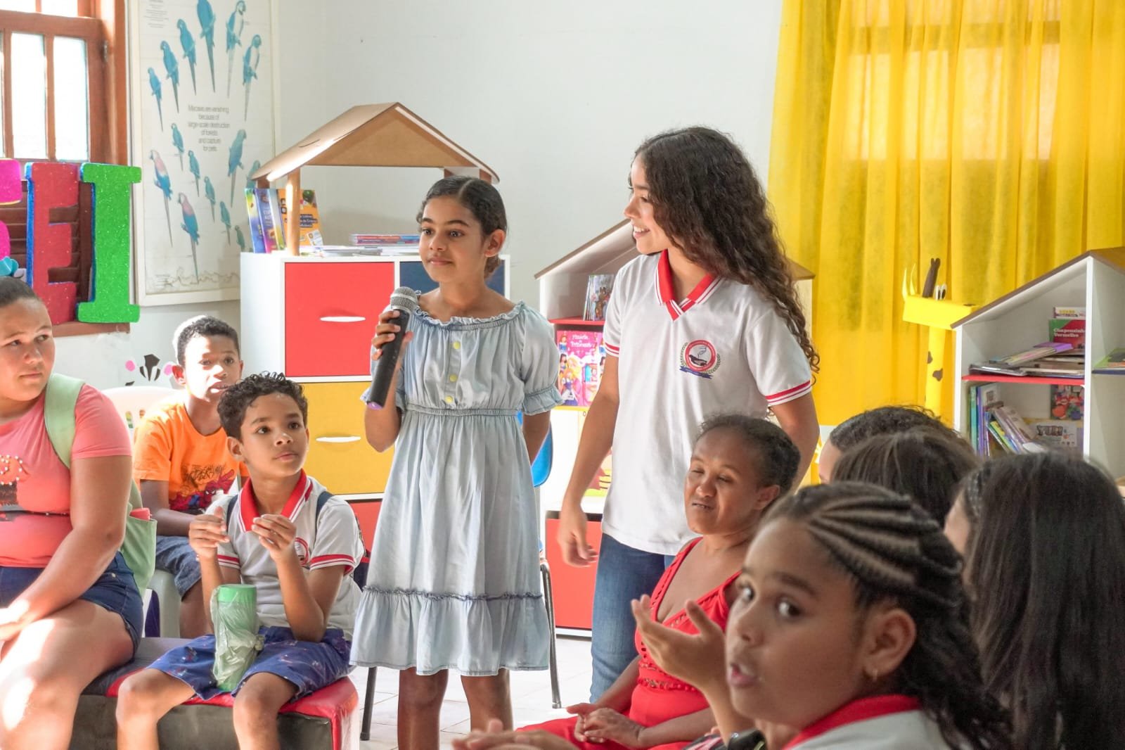 Estudantes com microfone em uma biblioteca escolar colorida